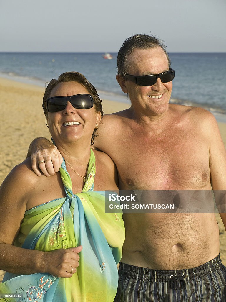 Coppia Senior divertendosi in spiaggia - Foto stock royalty-free di A petto nudo