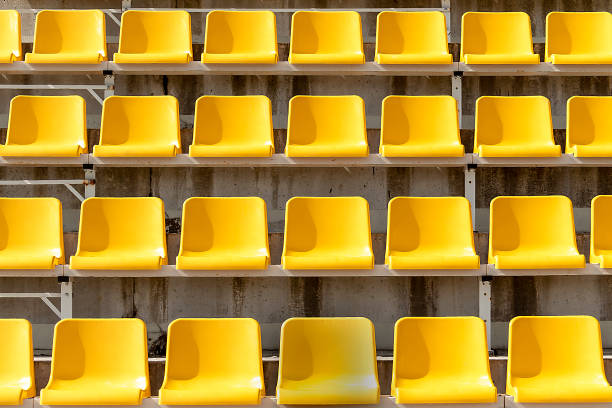 gelbe plätze auf tribünen des stadions in offen. zeilen sind horizontal. auf sitzen schatten von der sonne. - bleachers stadium empty seat stock-fotos und bilder