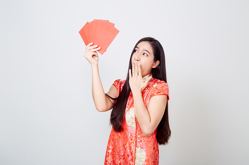 Asian women in chinese red dress feel happy with money in red envelopes on white background in Chinese new year