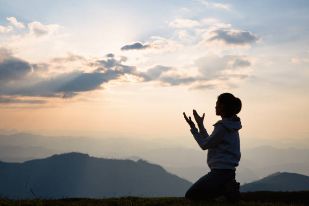 silueta de una mujer con las manos levantadas en el concepto de puesta de sol para la religión, la adoración, la oración y la alabanza, conceptos religiosos - adorando a dios fotografías e imágenes de stock