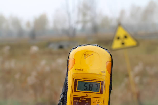 A dosimeter is held in front of a radioactivity warning sign, showing 5.87 millisieverts. Pripyat city, Chernobyl exclusion zone, Ukraine.