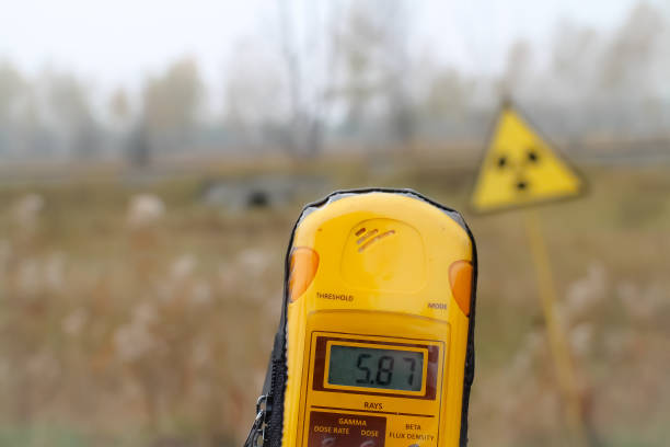 Dosimeter and radiation warning sign, Pripyat, Chernobyl exclusion zone A dosimeter is held in front of a radioactivity warning sign, showing 5.87 millisieverts. Pripyat city, Chernobyl exclusion zone, Ukraine. radiation dosimeter stock pictures, royalty-free photos & images