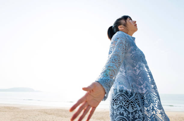 istock Woman standing on beach with arms outstretched 1189858646