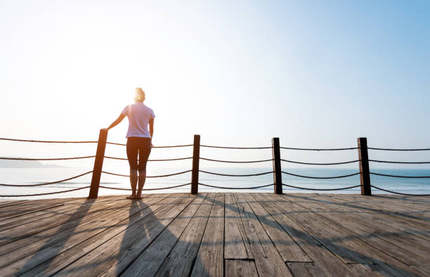 istock Woman standing on boardwalk at the beach 1189858681