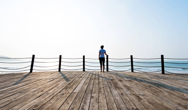 istock Woman standing on boardwalk at the beach 1189858721