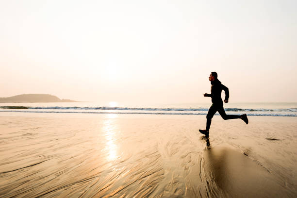 Man running on the beach at sunset.