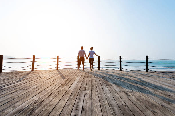 istock Couple standing on boardwalk at the beach 1189859887