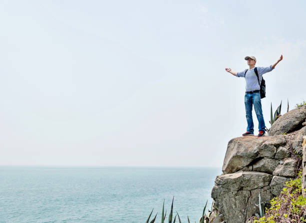 istock Man backpacker standing on the cliff by sea 1189860499