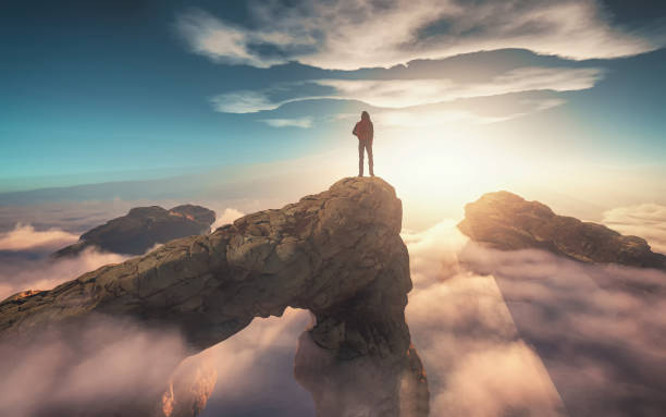 Traveler with a backpack standing on a mountain peak above clouds. 3d render illustration stock photo