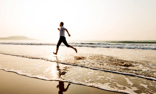 istock Man running on the beach at sunset 1189860694