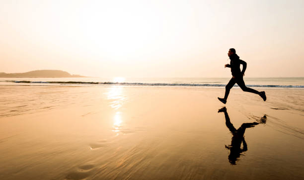 istock Man running on the beach at sunset 1189860889