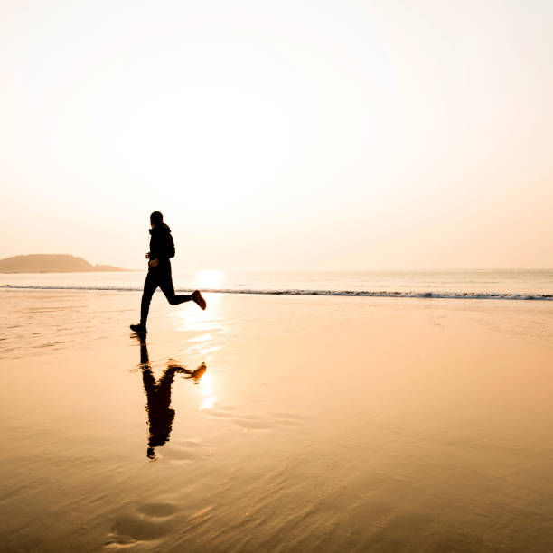 istock Man running on the beach at sunset 1189861130