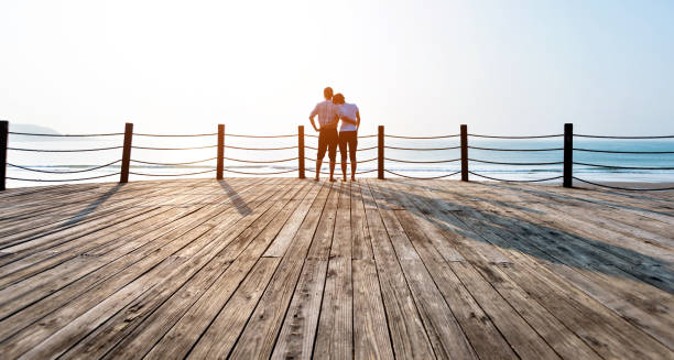 istock Couple standing on boardwalk at the beach 1189861207