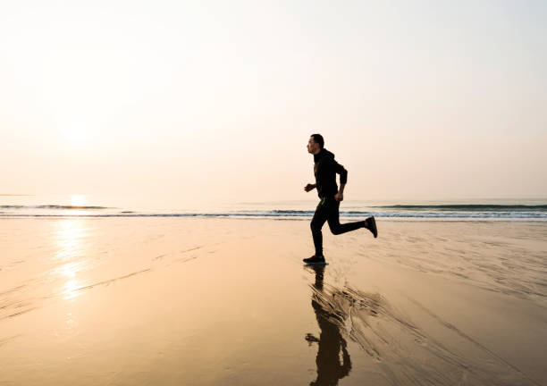 istock Man running on the beach at sunset 1189862065