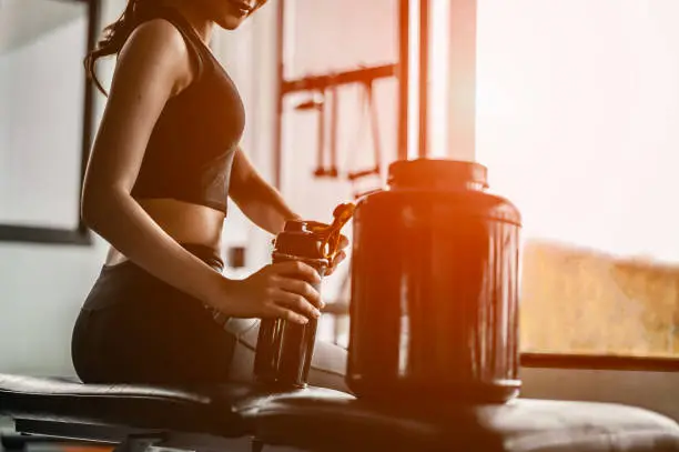 Relaxing after training.beautiful young woman looking away while sitting  at gym.young female at gym taking a break from workout.woman brewing protein shake.