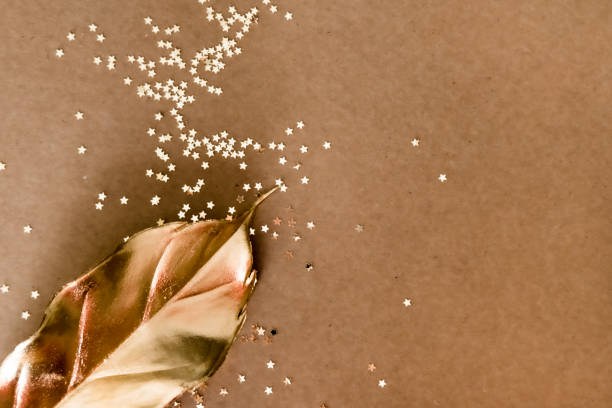Golden decorations and star shaped glitters on natural kraft background. Flat lay style. Holiday concept.