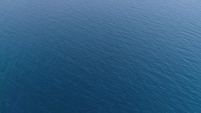 Aerial top down view from high altitude of blue azure  turquoise sea water texture. The camera flies over the water, a view of the water surface. Background of the water surface. 4K aerial view