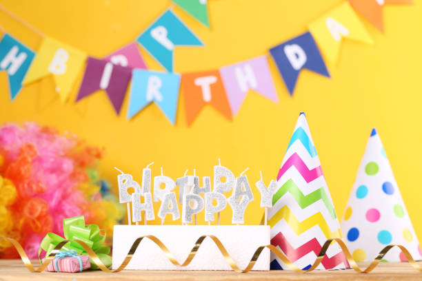 istock Happy Birthday candles with party decorations on yellow background 1189889423