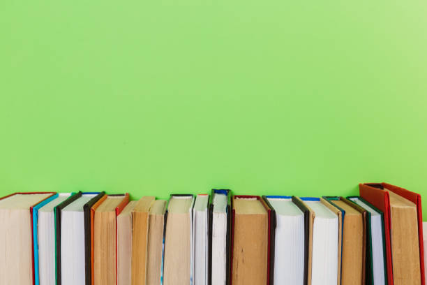 istock Simple Simple composition of many hardback books, unprocessed books on a wooden table and a green background. back to school. Copy space. Education. 1189889695