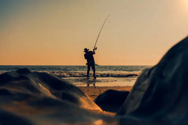 Man casting fishing rod in the water in the evening