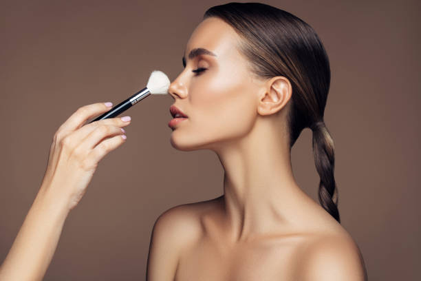 istock Beautiful young woman applying foundation powder 1189891021