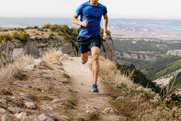 male runner running male runner running mountain trail on edge of cliff running shorts stock pictures, royalty-free photos & images