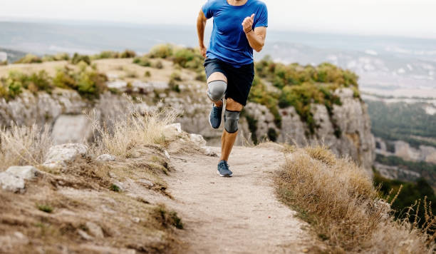 male runner running male runner running in knee pads on mountain trail kneepad stock pictures, royalty-free photos & images