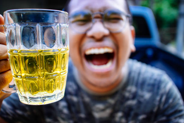 southeast asian man happily drinking beer
