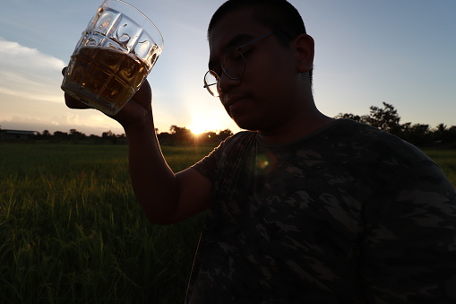 southeast asian man happily drinking beer