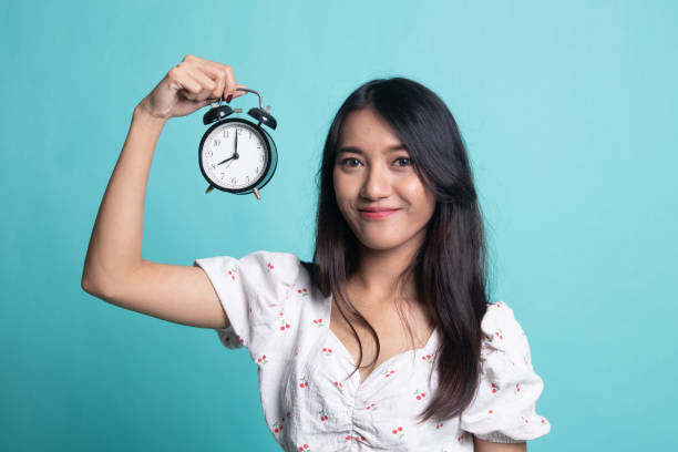 istock Young Asian woman with a clock. 1189899461