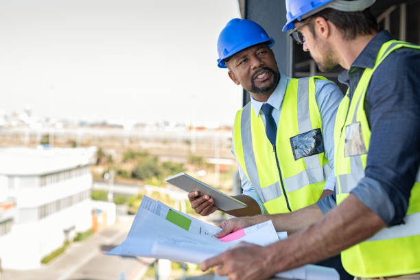 construction workers discussing blueprint - architect construction hardhat planning imagens e fotografias de stock