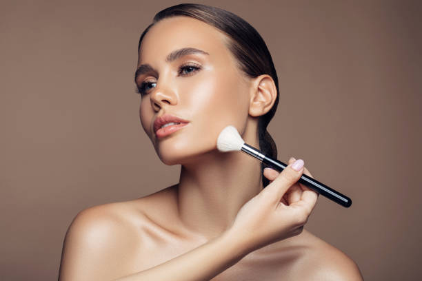 istock Beautiful young woman applying foundation powder 1189899672