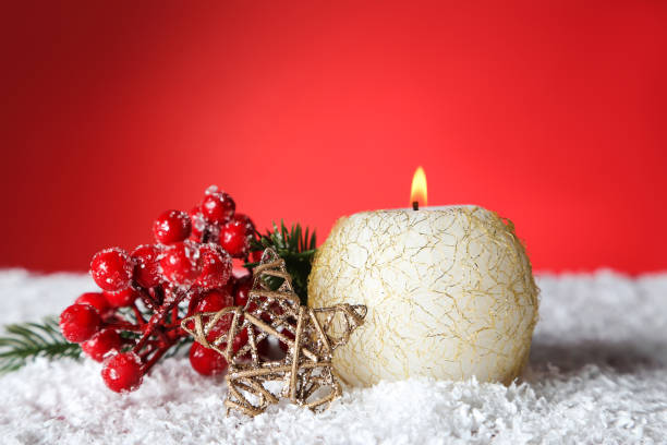 istock Christmas candle with decorative star and berries on red background 1189900106