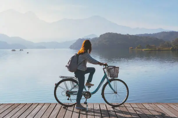 Photo of Young woman riding bicycle on Sun Moon lake bike trail, Travel lifestyle concept