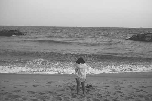 Rear view of a little girl is playing on a beach in the summer