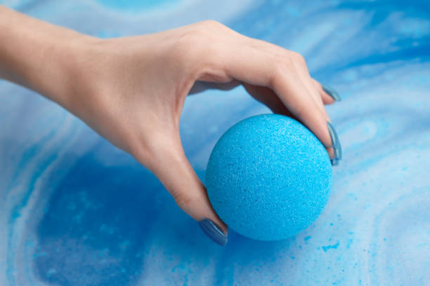 istock Woman's hand putting bath bomb into water 1189904875