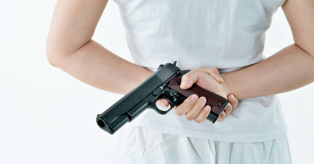 mujer mano sosteniendo un arma detrás de la espalda - gun women handgun armed forces fotografías e imágenes de stock