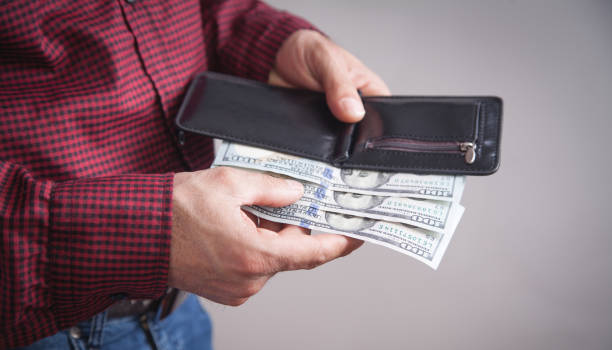 istock Man holding dollars with wallet standing over grey background. 1189907028