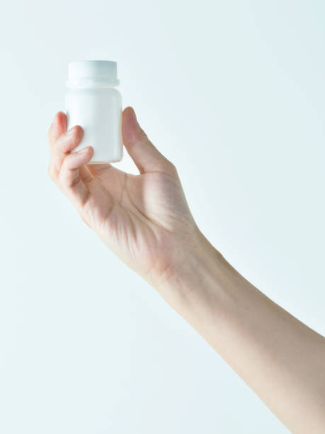 woman hand holding a white pill bottle - bottle vitamin pill nutritional supplement white imagens e fotografias de stock