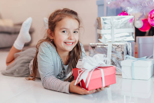 istock Smiling child lying under fir-tree with a gift wrapped for Christmas. 1189910183