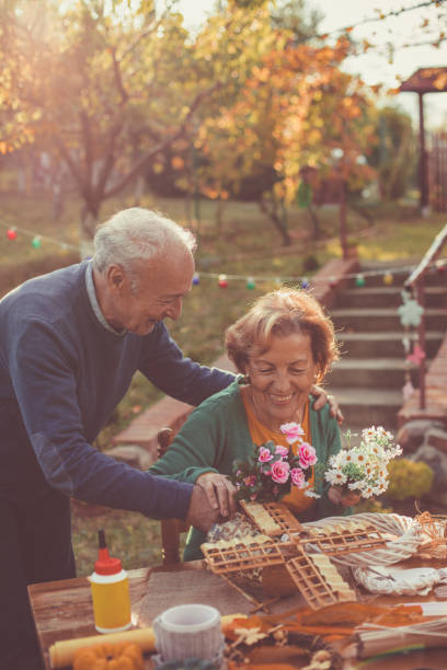 couples aînés faisant une couronne - autumn table setting flower photos et images de collection