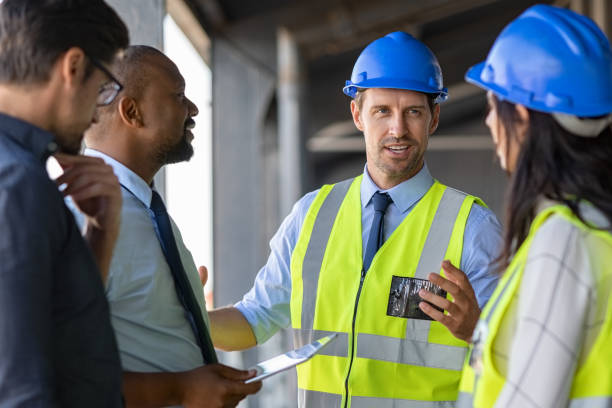 engineers and architects in conversation at building site - architect construction hardhat planning imagens e fotografias de stock