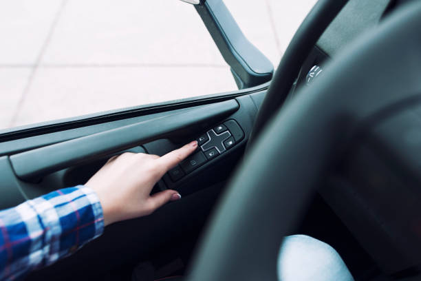 車両内の窓をロールアップするボタンを押すドライバーの手。 - roll of arms ストックフォトと画像