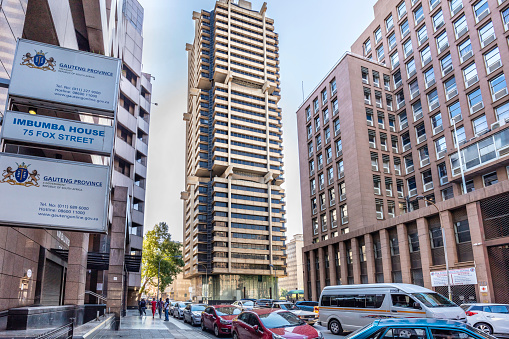 Imbumba House, Department of Treasury in Johannesburg with the old Standard Bank headquarters. This tower was built from the top down, meaning that after the central core was built, the floors were suspended from three cantilevered arms with the top floors added first, followed by each lower floor, then a government building on the right.