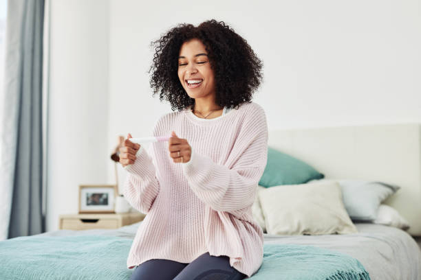 I'm going to be a mom! Cropped shot of an attractive young woman sitting on her bed alone and waiting for a pregnancy test result at home ovulation stock pictures, royalty-free photos & images