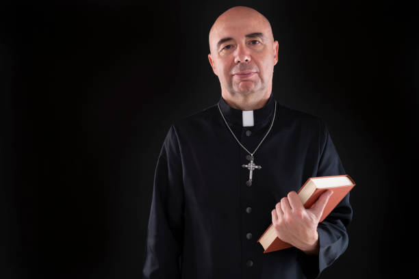 istock Priest holding bible hairless in low key black 1189921189