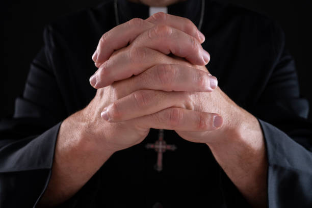 istock Priest cassock pastor praying with hands on black 1189921235