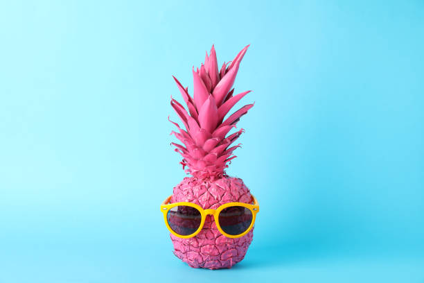 istock Painted pink pineapple with sunglasses on blue background, space for text 1189922514