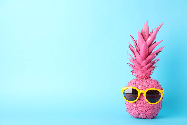 istock Painted pink pineapple with sunglasses on blue background, space for text 1189922585