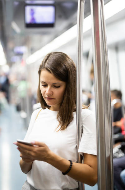 istock Female using mobile phone in subway car 1189922701